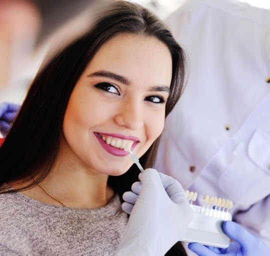Cosmetic dentist fitting a young woman with dental veneers