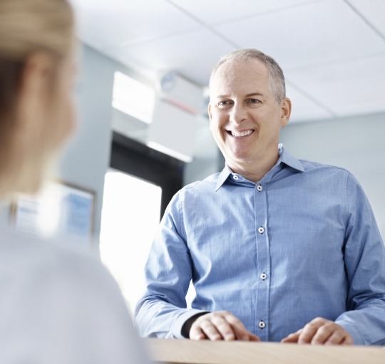 Man smiling at dental office receptionist