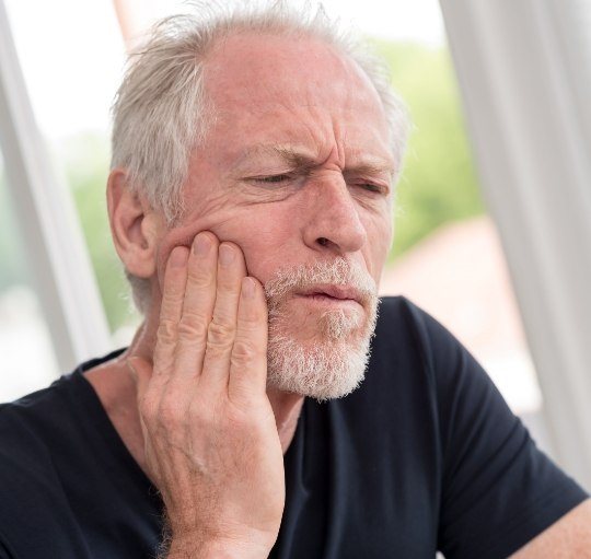 Man holding his cheek in pain before emergency dentistry in Honolulu