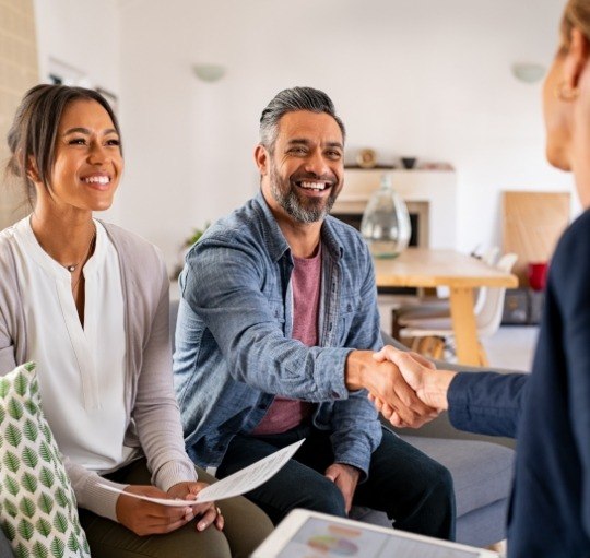 Smiling man shaking hands with dental team member