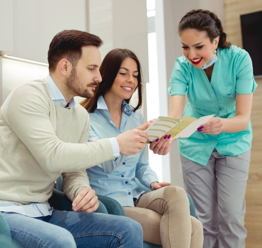 Dental team member showing a pamphlet to two patients