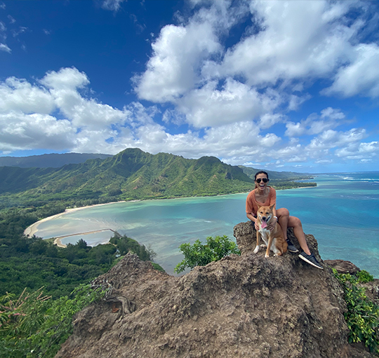 Doctor Koyanagi sitting on top of small mountain with her dog