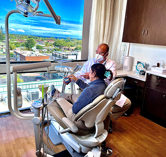 Honolulu dentist showing model of replacement teeth to a patient