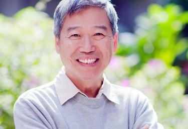 Man in gray sweater smiling after dental services in Honolulu