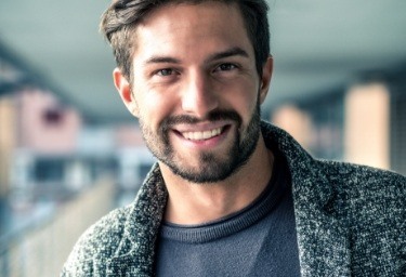 Young man in gray coat smiling