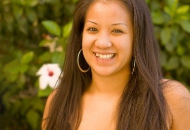 Woman with hoop earrings grinning outdoors