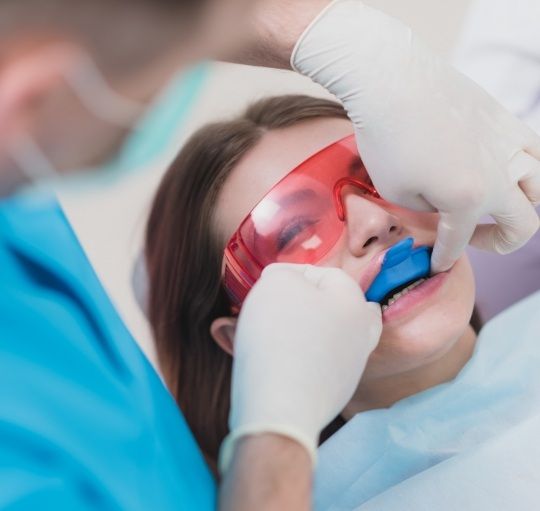 Woman in dental chair with fluoride trays over her teeth