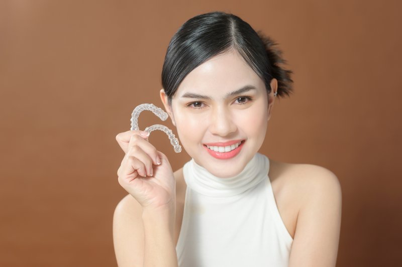 Lady smiles while showing Invisalign clear aligners